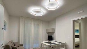 Una sala de estar moderna y minimalista con un sofá, una mesa de comedor y un televisor.