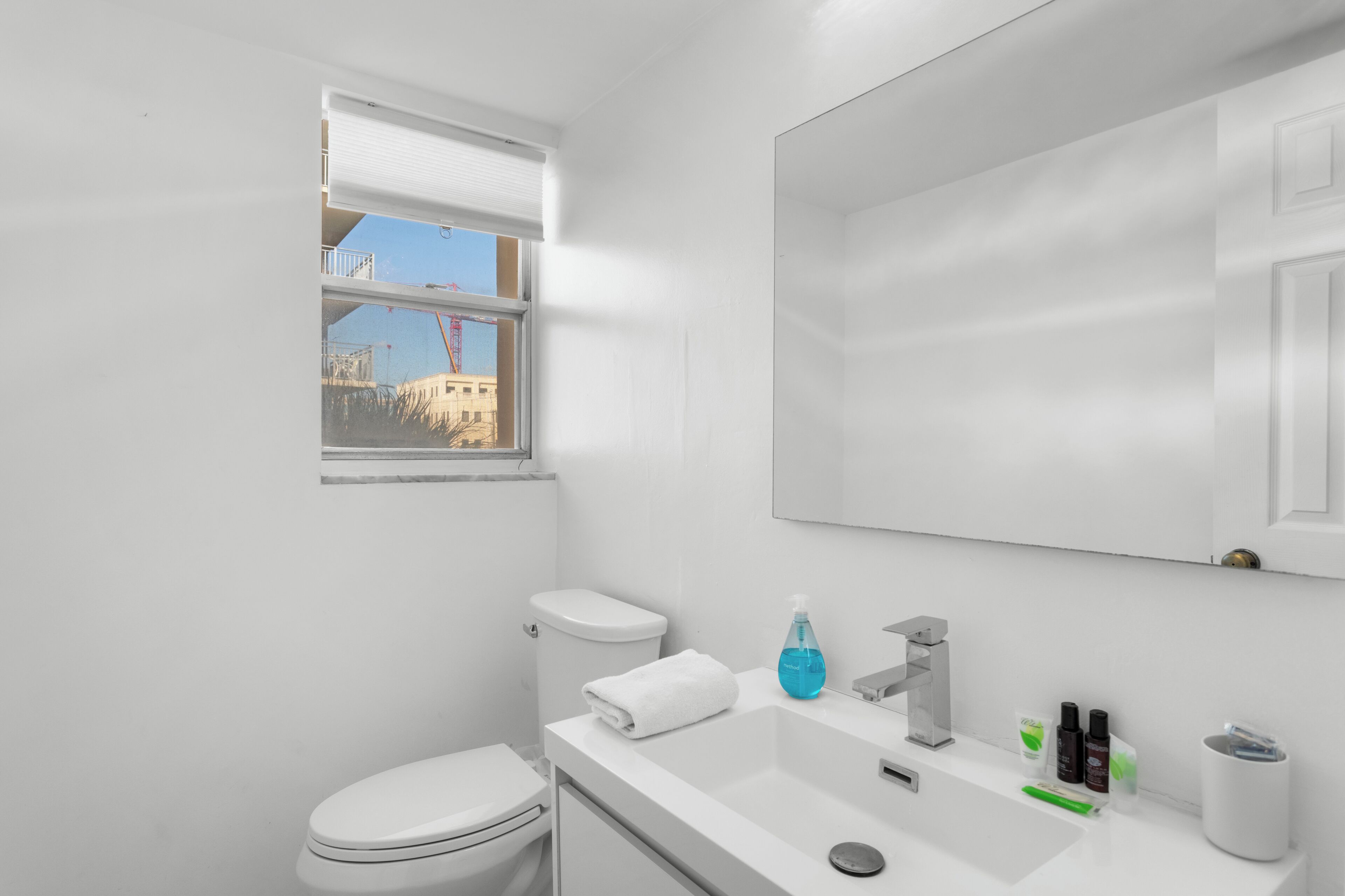 Une salle de bain moderne équipée de toilettes, d’un lavabo et d’une fenêtre.