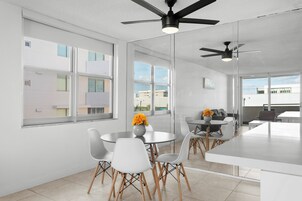 A modern kitchen with white cabinetry, a central island, and a dining area with white chairs and a round table.