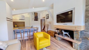 Una sala de estar moderna con un sillón amarillo, una chimenea y un televisor montado en la pared.
