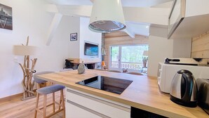Una cocina moderna con una isla de madera, horno empotrado y un amplio ventanal con vistas al exterior.