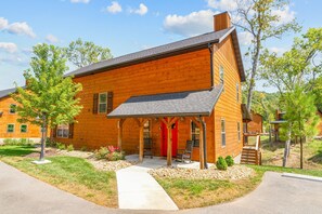 A two-story wooden house with a covered porch, a red door, and a number '200' on the side. - Cozy Cabin with Water Views, Private Hot Tub, Free Daily Tickets Near Table Rock (Hollister)