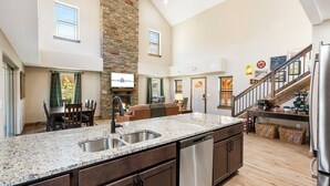 A spacious kitchen with granite countertops, a dishwasher, and a stone accent wall.