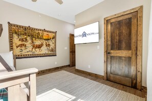 A room with a large tapestry, a wooden door, and a sign on the wall.