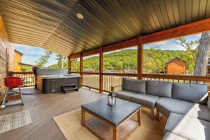 A covered outdoor area with a barbecue, seating, and a view of the surrounding forest. - Cozy Cabin with Water Views, Private Hot Tub, Free Daily Tickets Near Table Rock (Hollister)