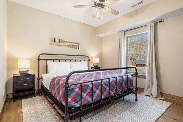 A neatly arranged bedroom with a bed, bedside tables, a ceiling fan, and a window with curtains. - Cozy Cabin with Water Views, Private Hot Tub, Free Daily Tickets Near Table Rock (Hollister)
