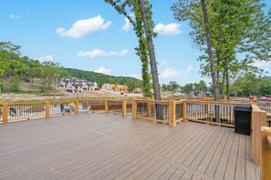Une terrasse en bois, dotée de rampes de protection, qui offre une vue sur un chantier de construction avec des bâtiments et des arbres.