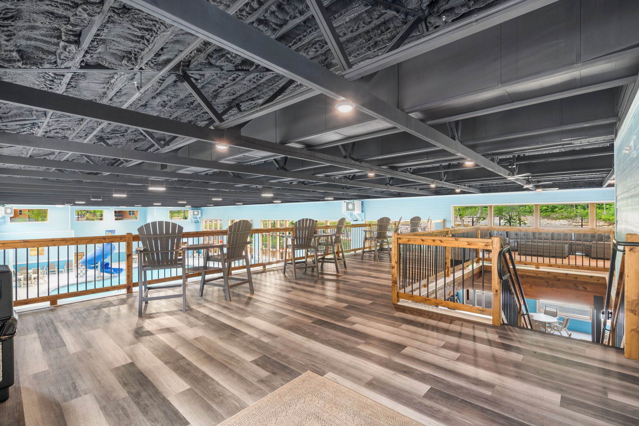 A spacious indoor area with a pool, wooden deck, and seating areas.