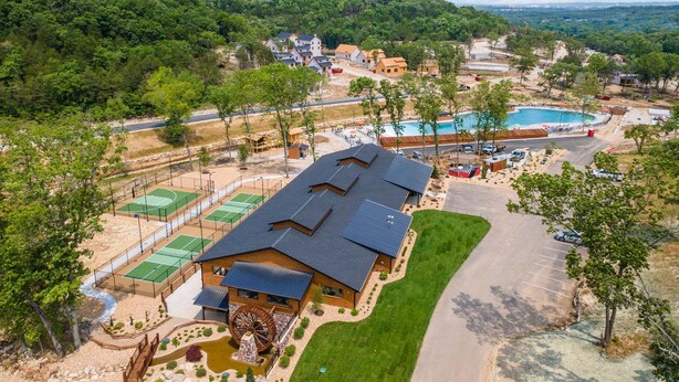 Un edificio grande con una rueda hidráulica, canchas de tenis y una piscina.