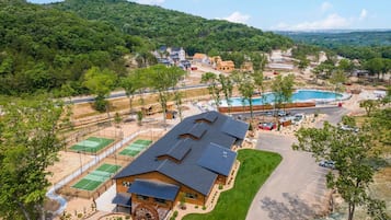 Ein großes Gebäude mit Wasserrad, Tennisplätzen und Schwimmbecken.