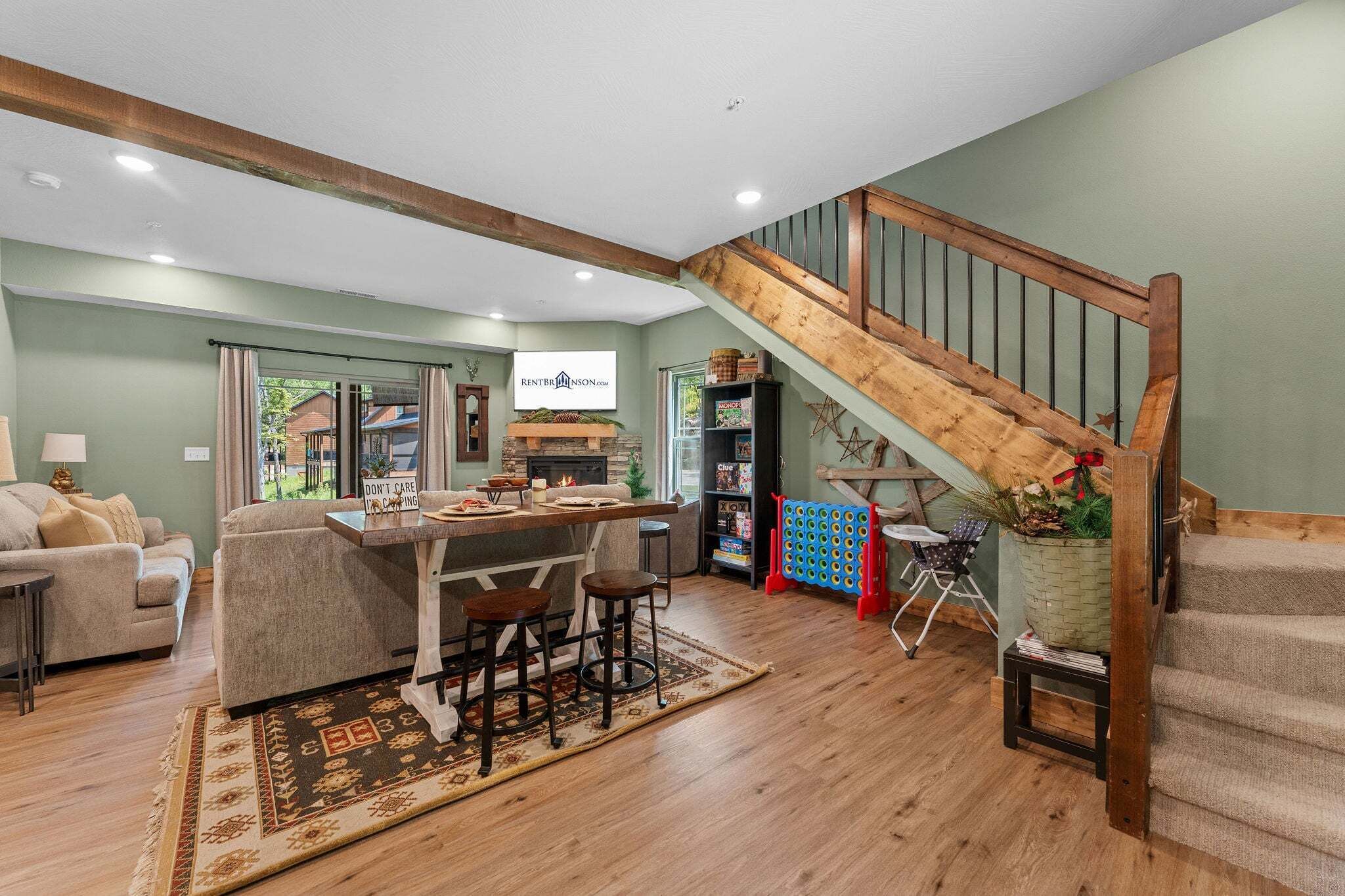 A spacious living area with a wooden staircase, a dining table, and a cozy seating arrangement.