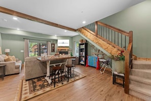 A spacious living area with a wooden staircase, a dining table, and a cozy seating arrangement.
