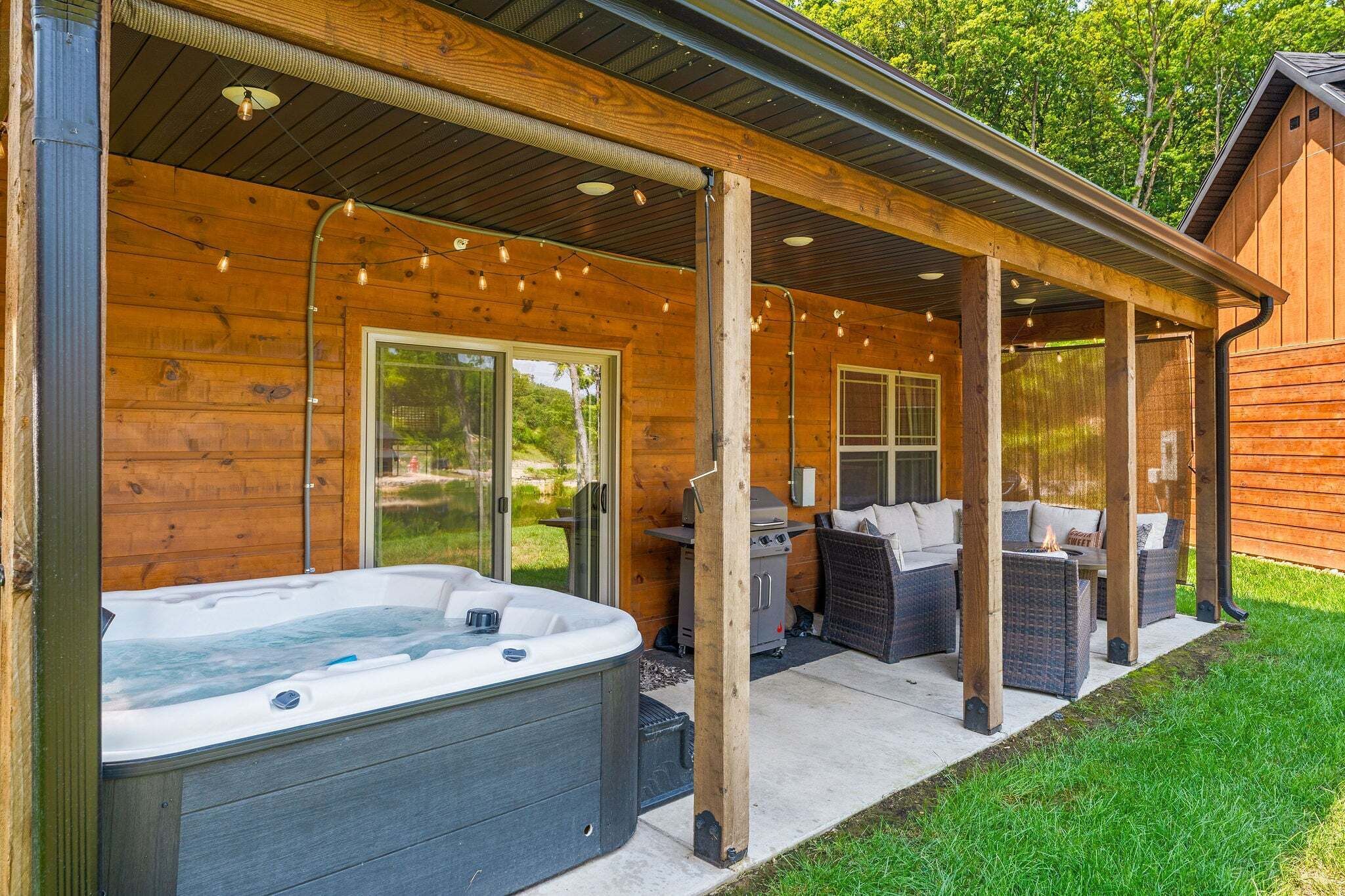 En træhytte med jacuzzi, udendørs møbler og en overdækket terrasse.