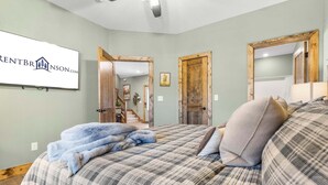 A bedroom with a large bed, a wooden door, and a framed picture on the wall. - Private Hot Tub Cabin Near Table Rock Lake with Firepit, Free Tickets & Community Experiences (Hollister)