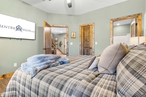 A bedroom with a large bed, a wooden door, and a framed picture on the wall.