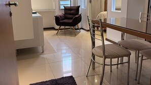 Una sala de estar moderna con un sofá, una mesa de comedor con sillas y un ventanal con cortinas.