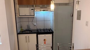 Una cocina moderna con armarios blancos, un refrigerador de acero inoxidable, una estufa a gas y una mesa de madera con sillas de metal.