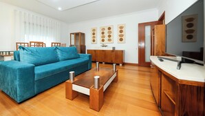 Un salon moderne avec un canapé bleu, une table basse en bois et un téléviseur posé sur un meuble en bois.