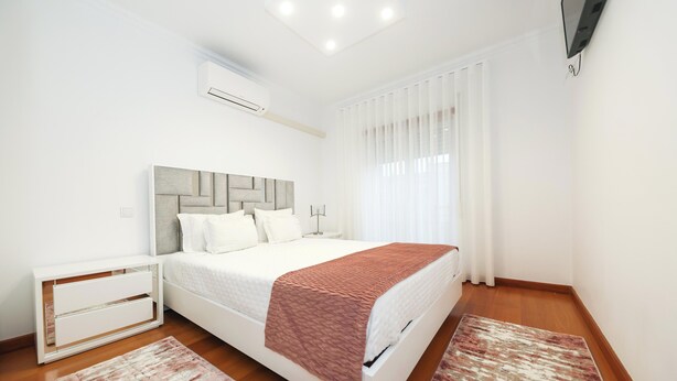 Une chambre moderne avec un lit, des tables de chevet et une grande fenêtre avec des rideaux.