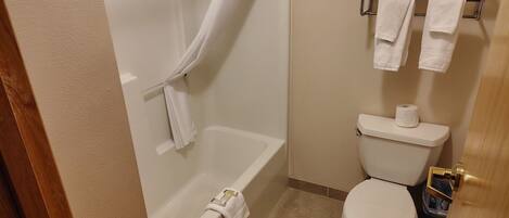 A bathroom with a bathtub, toilet, and towel rack.