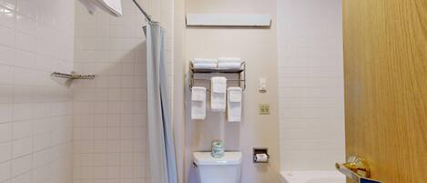 A bathroom with a shower, toilet, and bathtub.