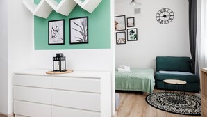 A modern living room with a white console, a green sofa, a round coffee table, and a patterned rug.