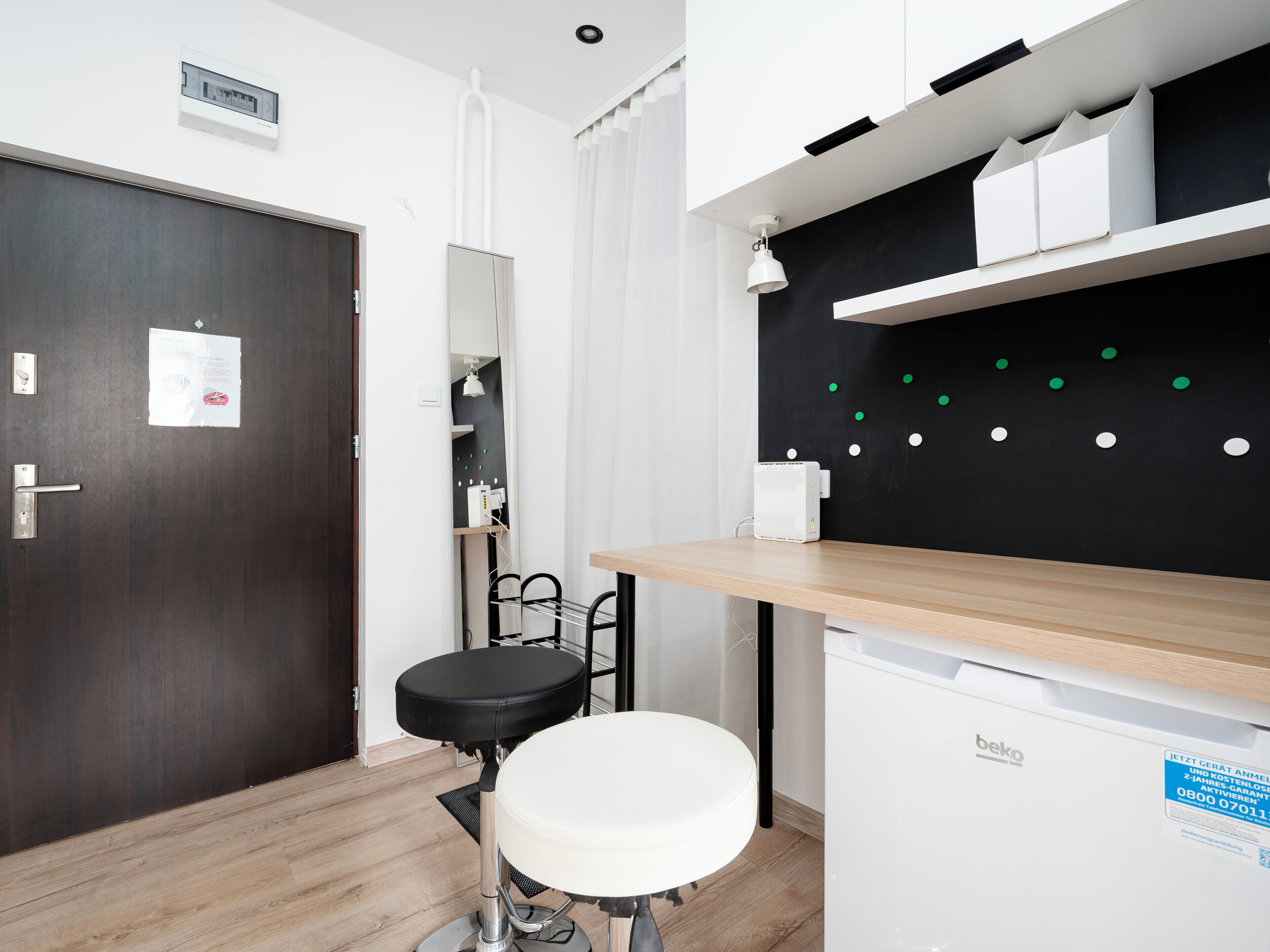 Une salle de bain moderne avec un plancher en bois, un lavabo blanc, une chaise noire et un miroir.