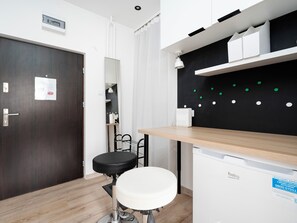 A modern bathroom with a wooden floor, a white sink, a black chair, and a mirror.