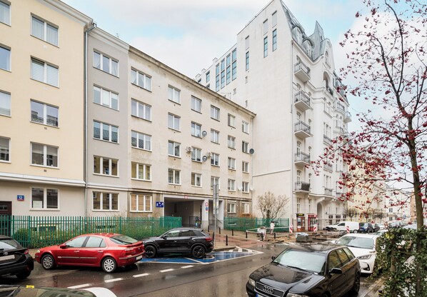 Un edificio residencial de varios pisos con un área de estacionamiento al frente.