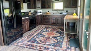 Una cocina moderna con armarios de madera oscura, electrodomésticos de acero inoxidable y una alfombra estampada.