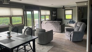 Amplia sala de estar con mesa de comedor, sofás grises y ventilador de techo.
