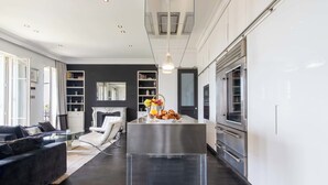 Eine moderne Küche mit Kochinsel, integrierten Geräten und einem Essbereich mit weißem Sofa und Kamin.