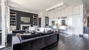 Ein modernes Wohnzimmer mit einem dunkelgrauen Sofa, einem weißen Sessel und einem Kamin.