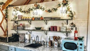A kitchen with a vintage microwave, shelves with jars and plates, and a decorative garland. - Unique Stay! Yurt with Mountain View, 1 min to Breweries & Hiking, 5 min to Lake (Roseland)