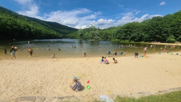A sandy beach with people swimming and relaxing in a lake surrounded by forested hills. - Unique Stay! Yurt with Mountain View, 1 min to Breweries & Hiking, 5 min to Lake (Roseland)