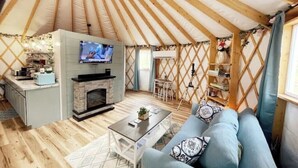 A cozy interior of a yurt with a television, fireplace, sofa, and a dining area. - Unique Stay! Yurt with Mountain View, 1 min to Breweries & Hiking, 5 min to Lake (Roseland)