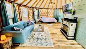 A cozy interior of a yurt with a sofa, a small table, a bed, and a fireplace. - Unique Stay! Yurt with Mountain View, 1 min to Breweries & Hiking, 5 min to Lake (Roseland)
