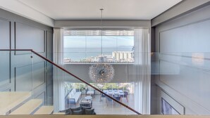 Ein modernes Interieur mit einer Treppe, die zu einem Balkon mit Blick auf eine Stadtlandschaft führt.