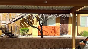 Un área de estacionamiento con una sección cubierta, un árbol y un edificio con el letrero número 152.