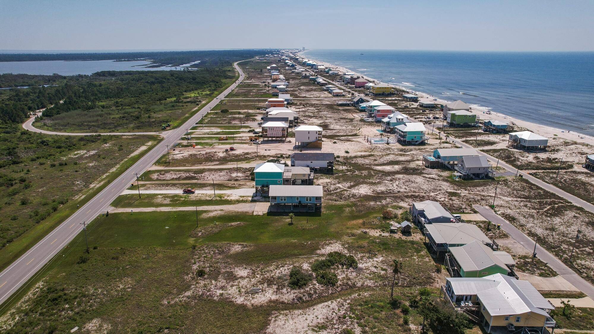 An aerial view of a coastal development with multiple buildings, roads, and a beach.