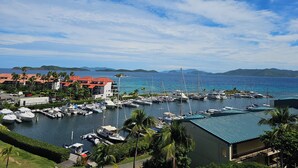 A marina with boats docked, surrounded by buildings with red roofs and palm trees.