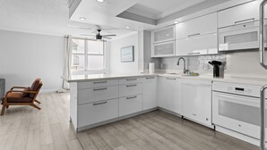 A modern kitchen with white cabinetry, a built-in oven, and a ceiling fan. - Bay Harbor Sunset Apt 5A (Bay Harbor Islands)