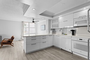 A modern kitchen with white cabinetry, a built-in oven, and a ceiling fan.