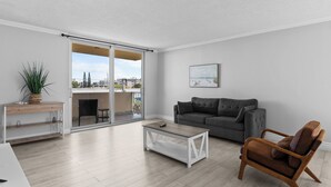 A modern living room with a grey sofa, a wooden coffee table, and a brown leather armchair. - Bay Harbor Sunset Apt 5A (Bay Harbor Islands)