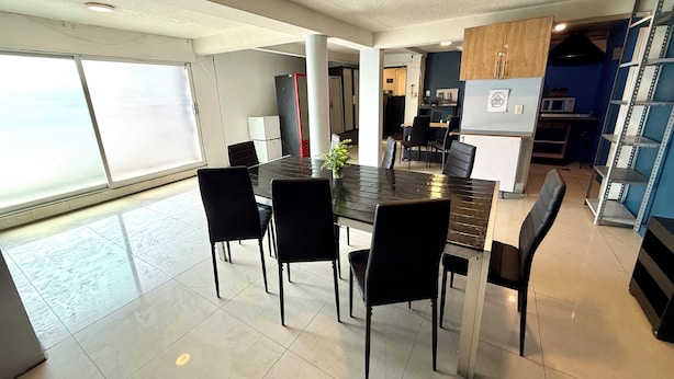 A modern kitchen with a large dining table, black chairs, and a refrigerator. - WONDER HOSTAL - Santa Maria (Mexico City)