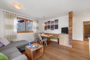 Een moderne woonkamer met een bank, een eettafel en een televisie.