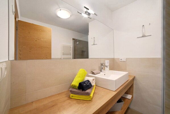 A bathroom with a wooden vanity, a white sink, and a mirror.