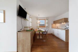 Een moderne keuken met een eethoek, houten kastjes, een flatscreen televisie en een raam met uitzicht.