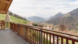 A balcony with a wooden railing overlooking a valley with houses and mountains. - Apartment 'Thymian' with Mountain View, Private Terrace and Wi-Fi (Schenna)