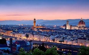 Paesaggio urbano con architettura storica ben visibile, tra cui una torre e una cupola, al crepuscolo.